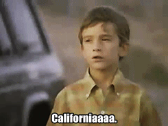 A young white boy standing outside of a car saying Californiaaaa.