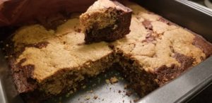 A pan of brookies cut into bars, with two bars missing. One bar sits on top of the other bars.