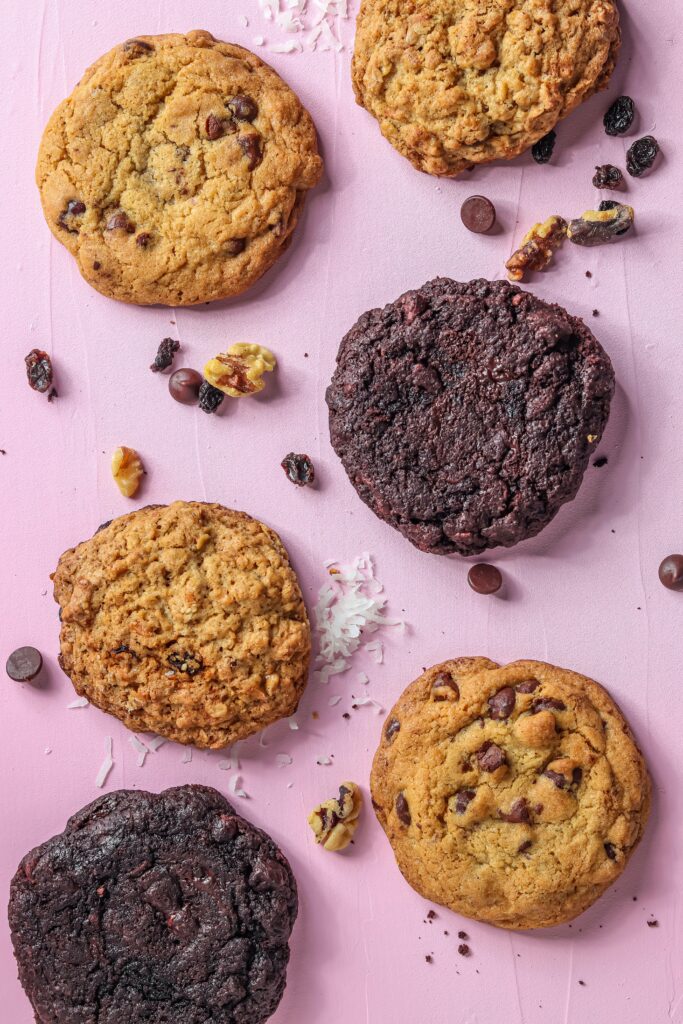 Two columns of three cookies of different varieties, including chocolate, chocolate hip, and oatmeal raisin.