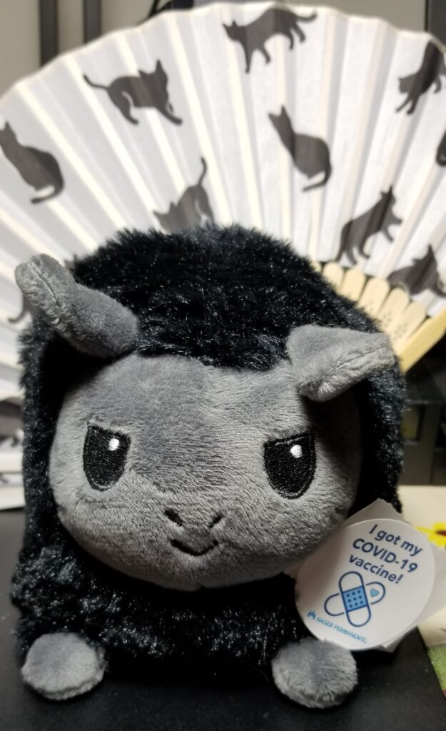 A black plushie llama wearing a "I got my COVID-19 vaccine!" sticker.