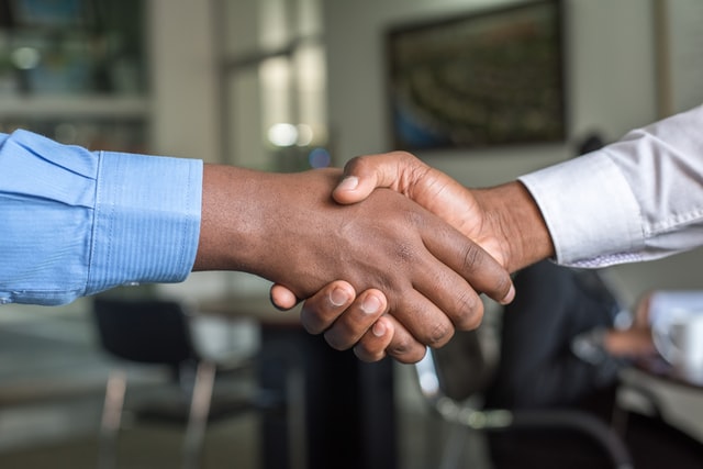 A handshake between two people in an office setting.