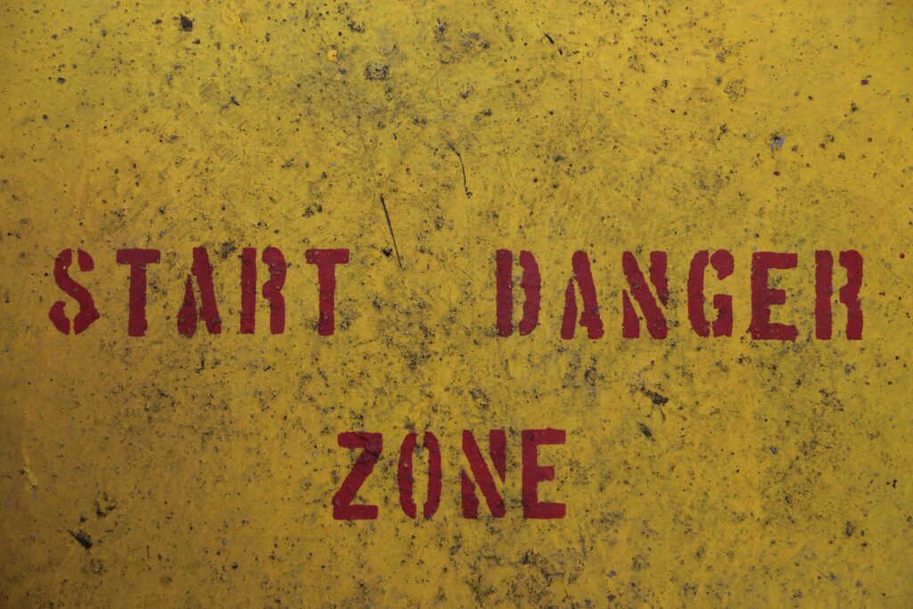 Red spray painted text on a yellow metal background - "START DANGER ZONE".